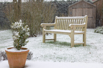 Back yard backyard with garden bench in snow. UK winter gardens
