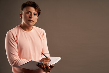 latin man writing in notebook standing facing front