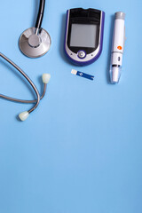 Medical concept on blue background stethoscope, lancet handle, glucometer. Vertical photo, close up with copy space. Diabetes concept