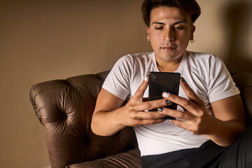 latin man on a sofa using a telephone black white painted nails