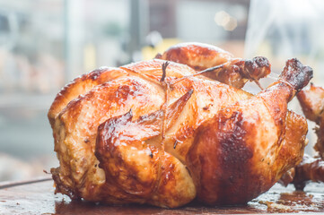 roasted chicken with chicken machine in the background, copy space and natural light, man holding a skewer with several chickens