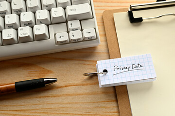 There is  word book with the word of Privacy Data. It's on the desk with a clipboard and a keyboard.