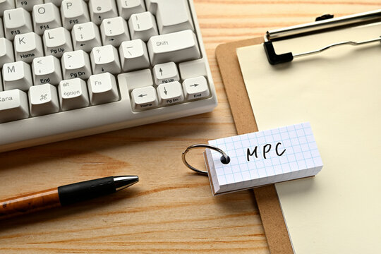 There is a word book with the word of MPC which is an abbreviation for marginal propensity to consume on the desk with a pen and a keyboard.