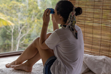 young woman sitting on wooden floor admiring forest view, relaxing.