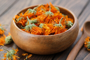 Dried healing calendula marigold flowers in a wooden bowl. Alternative herbal medicine. - obrazy, fototapety, plakaty