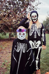 Two sisters dressed up as skeleton and witch having fun at Halloween party and trick-or-treating...