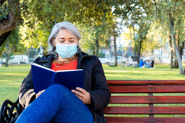 Fototapeta premium Mature woman with gray hair reading a book at park