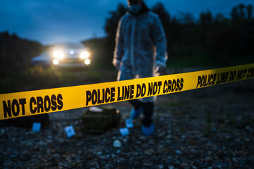 Forensic police investigator collecting evidence at the crime scene by the river in nature at night...