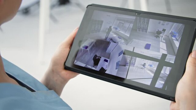 surveillance camera application, young woman with digital tablet in her hands is watching room using video camera, close-up