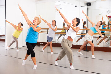 Naklejka na ściany i meble Group of various aged women dancing modern dance in studio.