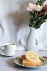 Lemon pound cake with slices of lemon and cup of coffee. Rose flower with dessert. Delicious breakfast, traditional. Vintage concept.