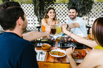 Group of Young latin Friends Meeting For beer, michelada Drinks And mexican Food Making A Toast In Restaurant terrace in Mexico Latin America	