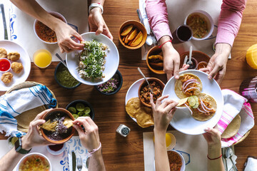 group of Friend eating Mexican Tacos and traditional food, snacks and peoples hands over table, top view. Mexican cuisine	