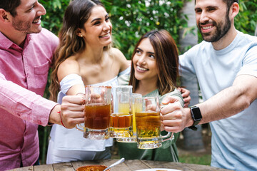 Group of Young latin Friends Meeting For beer, michelada Drinks And mexican Food Making A Toast In Restaurant terrace in Mexico Latin America	