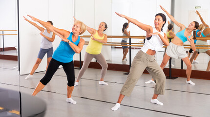 Naklejka na ściany i meble Positive women practicing vigorous dance movements in group dance class