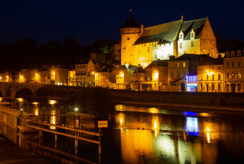 View from Mayenne river of illuminated castle and bridge of Laval town at summer night, southwestern France