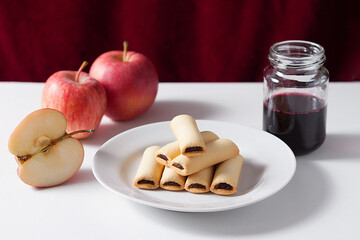 Apple cookies on a white table. Apple filled biscuits and a jar of blueberry jam.