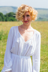 Fototapeta na wymiar Beautiful blonde woman with short curly hair outdoors.