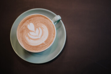 Top view of a cup of frothy coffee on a dark table