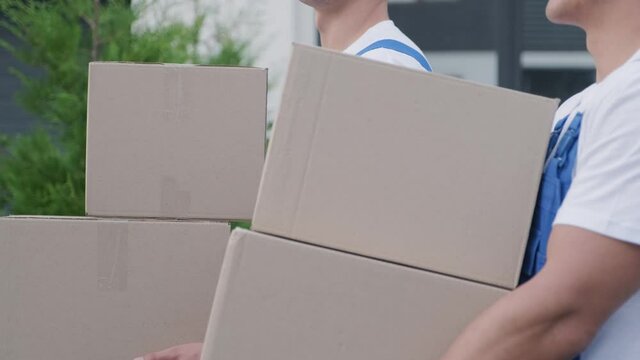Two young workers of removal company deliver boxes to a customer's home