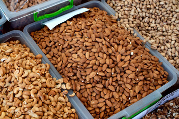 Different nuts: almonds, cashews, pistachios on display at farmer's market. Real food backround. Vegetarian and healthy eating concept