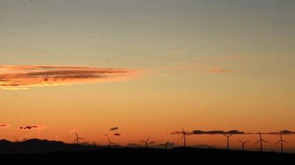 Silhouette of windmills on top of the hills with the sunset behind in New Zealand