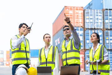 Group of Diversity factory worker people man and woman standing in front of containers logistic in warehouse. asian, and white caucasian people operate on site cargo for logistic shipping area.