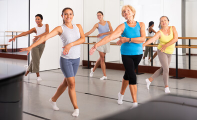 Fototapeta na wymiar Positive women of different ages dancing strip plastic in a dance class