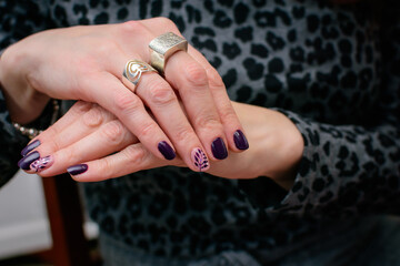 Manos de mujer con anillos y uñas pintadas con fondo animal print