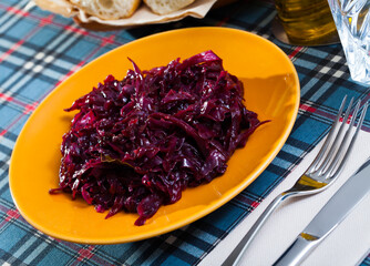 Traditional stewed red cabbage served on yellow plate. Delicious vegetarian food..