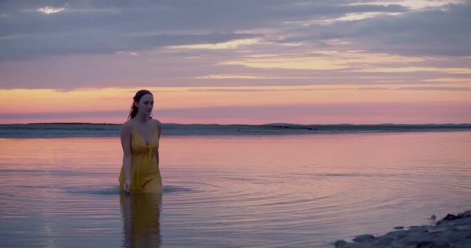 Beautiful wet female walking out of water wearing yellow dress with perfect body shapes