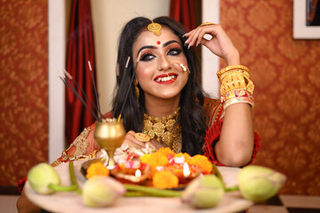 Portrait of pretty young Indian woman wearing traditional saree, gold jewellery and bangles, smiles tender in studio lighting indoor. Indian culture, occasion, religion and fashion.