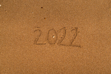 Happy New Year 2022 on the beach. Sand on a beach with a wave by the sea. Winter Vacation on the sea. New Year concept. Top view