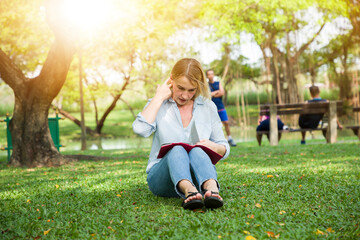 Woman sitting on green grass and reading a book the park, Girl reading a book