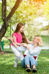 Fototapeta premium Happy mother and cute daughter playing in park and summer day