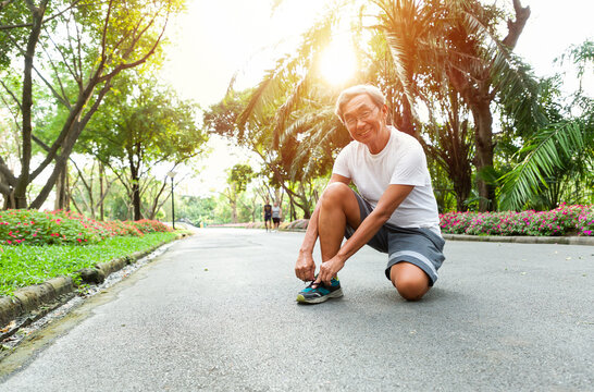 Senior man wearing glasses preparing for a run in the park, Warm up before running, exercise before start jogging.
