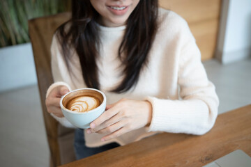 Smiling woman in sweater holding cup of coffee.