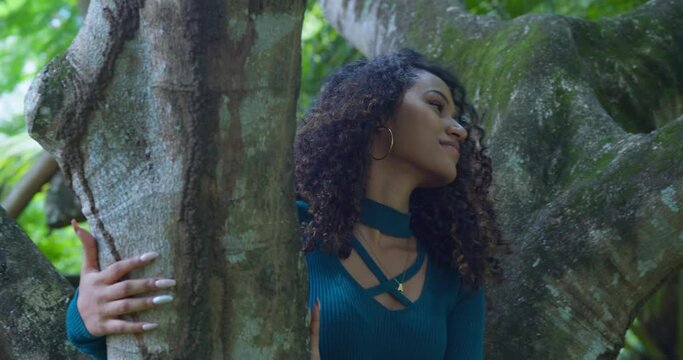 Curly hair girl sits in a tree while enjoying a sunny day