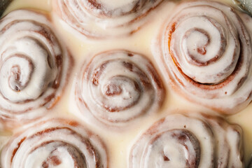 Tasty baked cinnamon rolls with icing, closeup