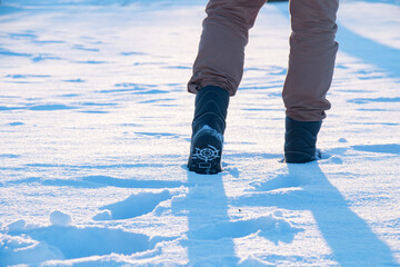 A man in boots walks through the snowdrifts. Walk in the snow on a frosty winter day.