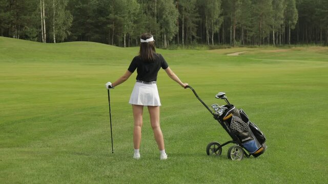Young woman on golf course, back view.