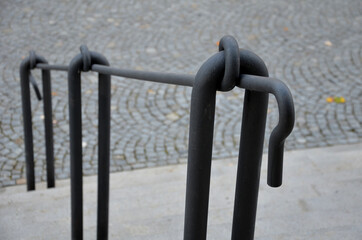 wide stone staircase with railings in the middle of the ramp. forged design railing made of solid tubes connected by knots and loops. a true master blacksmith will make such elegance