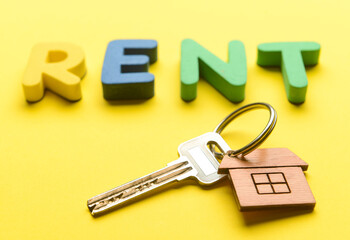 Word RENT with key from house on yellow background, closeup