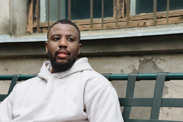 Obraz premium Freedom search concept. Young African American sitting on a bench, windows behind bars