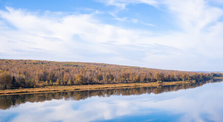 Beautiful, wide river autumn among the woods. Calm and quiet place with autumn colors. In the middle of the river island. View from the top to the distance
