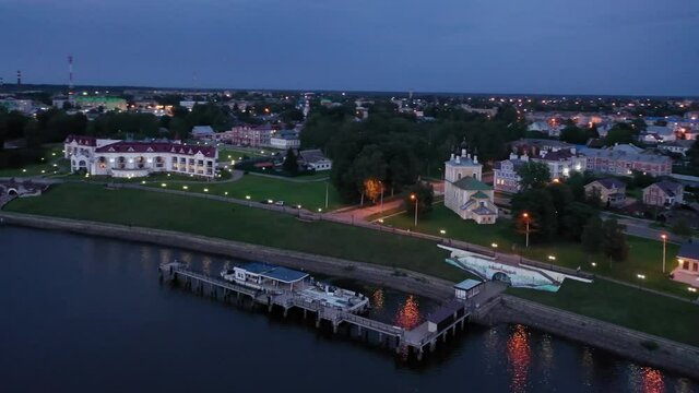 Picturesque aerial view of illuminated townscape of Uglich overlooking Kremlin cathedrals on banks of Volga River on summer twilight, Yaroslavl region, Russia. High quality 4k footage