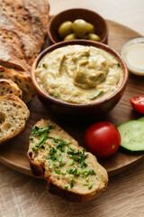 Bowl with tasty baba ghanoush, bread and vegetables on wooden background, closeup