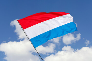 Luxembourg flag isolated on the blue sky background. close up waving flag of Luxembourg. flag symbols of Luxembourg. Concept of Luxembourg.
