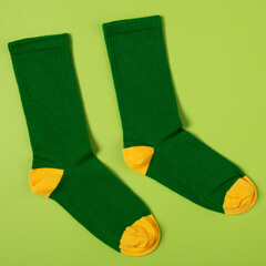 pair of stylish green socks with yellow heels and toes, on green background, concept - obrazy, fototapety, plakaty