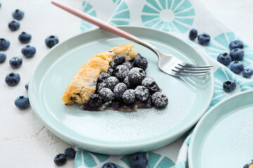Plate with piece of tasty blueberry galette on light background, closeup